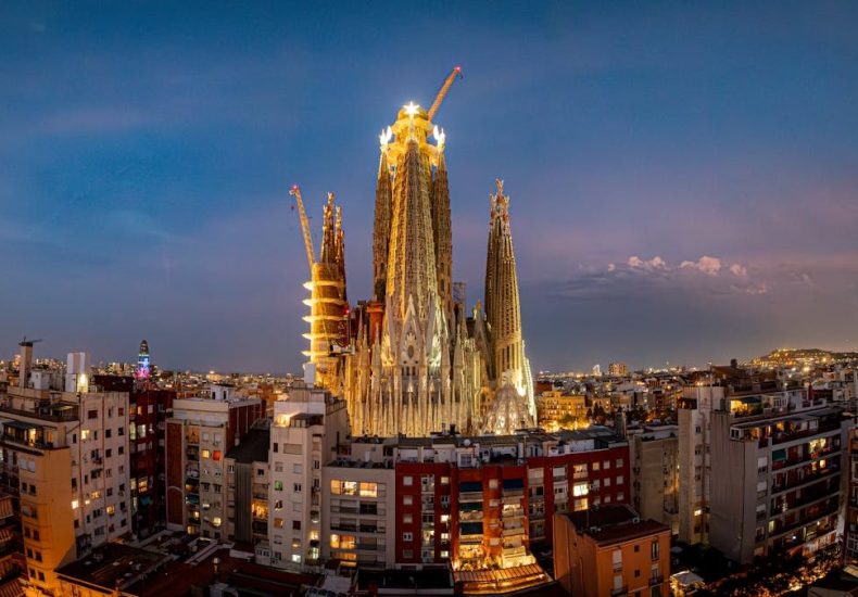 Sagrada Família illuminated at twilight in Barcelona, showcasing its intricate architecture against the cityscape.