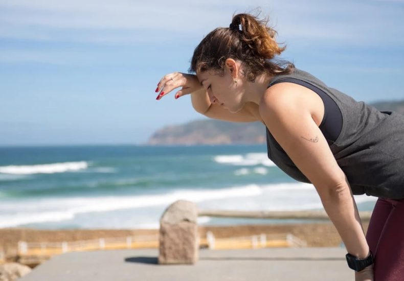 A woman rests after exercise, overlooking the ocean in Portugal's scenic seascape.